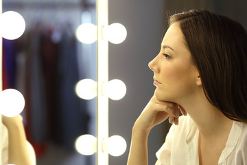 Serious woman looking at make up mirror