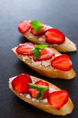 On a fashionable dark stone surface set sandwiches with cheese and strawberries, decorated with mint, tasty, healthy, breakfast, beautiful serve, berries, summer