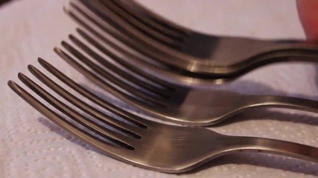 Unfolds polished steel forks on a white napkin