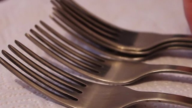Stacks polished steel forks on a napkin