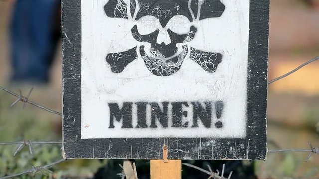 attention - mines! skeleton sign closeup. warning message on german language on wooden surface, security diversity