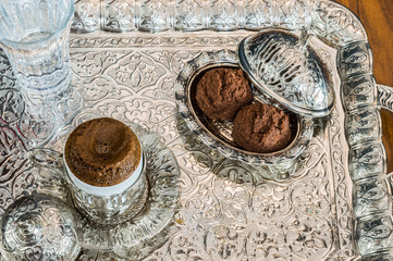Turkish coffee served with water and cookies in traditional copper serving set