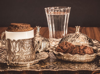 Turkish coffee served with water and cookies in traditional copper serving set