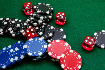 Poker chips and dice on a green gaming table top view copyspace close up
