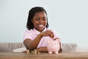 Girl Inserting Coins In Piggy Bank
