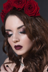 beautiful young woman with roses flower in hair. beauty girl with make-up over dark background. dark red lips.close-up fashion retouched portrait