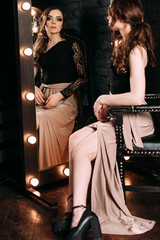 Individuality. Thoughtful Elegant Lady in Black Prom Dress standing near mirror on dark background. fashion retouched shot