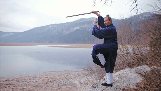Warrior posing with sword next to frozen lake