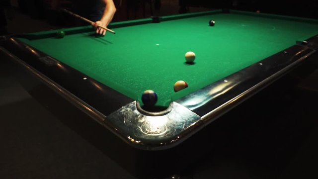 Playing billiards, blowing a cue on the ball, the ball hit the pocket, the ball did not hit the pocket, misfire, hit, American billard, pool, green billiard table, the man plays billiards, breaking