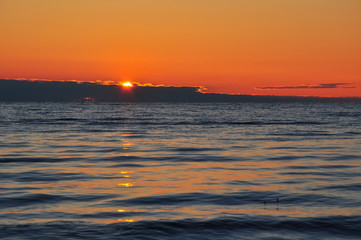 Fototapeta premium Dawn at the Ladoga. The sun rising above the lake reflecting in the waves
