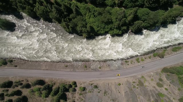 Overhead Horizontal Aerial of Cars Driving in Nature on Mountain Highway by Raging River