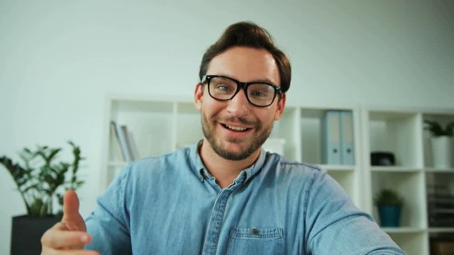 Happy atractive business man in the glasses having a video conference in a modern stylish office room.