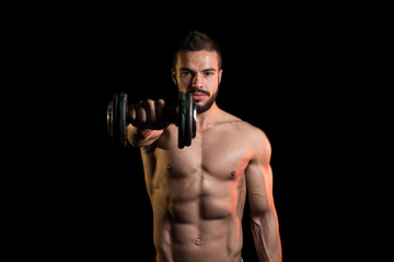 Fototapeta na wymiar Model Exercising Shoulders With Dumbbells On Black Background