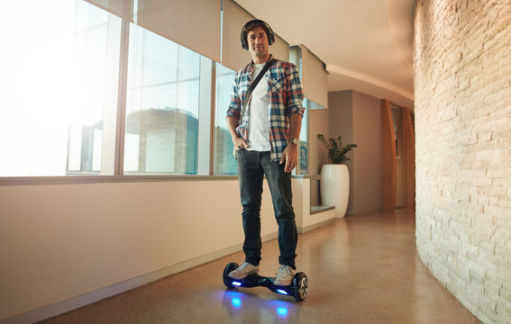 Young man on an electrical self-balancing scooter in office