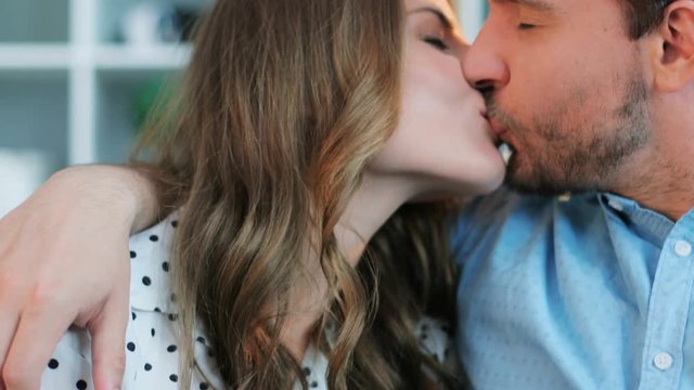 Portrait of young couple in love looking at each other, woman holding the hands of man with gentle while sitting on the sofa.