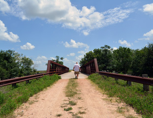 Fototapeta premium Crossing the Trestle Bridge/Lonely Man walking across a gravel steel trestle bridge