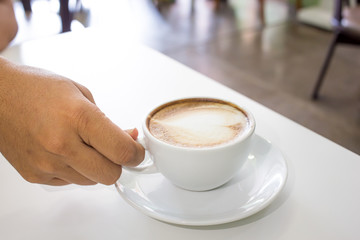 hand holding Espresso Coffee cup on wood table in cafe