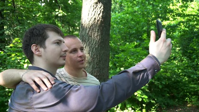 two young men take a selfie in the forest.