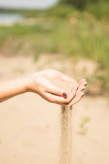 sand running through hands of woman
