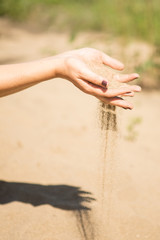 sand running through hands of woman
