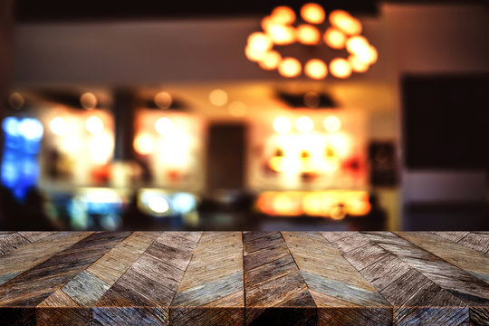 Empty old grunge wood plank table in front of blur restaurant nightclub bar bokeh light background,Mock up for display or montage of product or design
