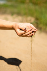 sand running through hands of woman