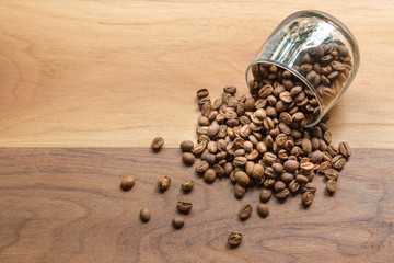 coffee beans in a coffee cup on wooden table. top view of medium roasted coffee beans for coffee drip on wooden table background with copyspace.