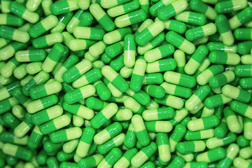 heap of green pill capsules waiting to be pack or filling at the container in medical factory. medical concept photo and background. selective focus.
