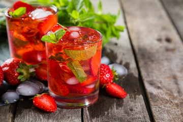Strawberry mojito and ingredients on rustic background