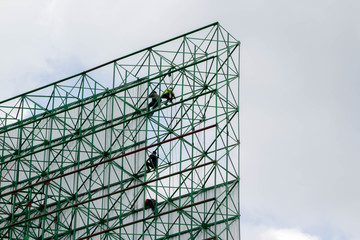 workers installing metal sheets on big billboard
