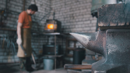 Fototapeta na wymiar The blacksmith in forge near furnace