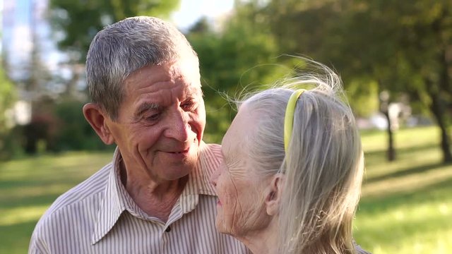 Close-up of happy elderly couple with grey hair and wrinkles in the Park looking at each other