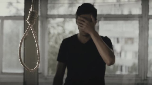 Suicide. Depressed man crying on the background of the loop for the neck.