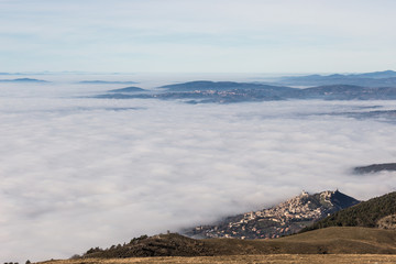A view of Assisi town and St.Francis church over a sea of fog, with distant hills and Perugia city in the background