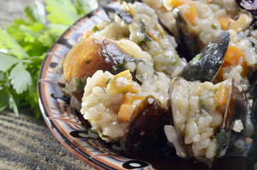 Risotto with mussels  in the plate on a wooden old table/paella/,selective focus