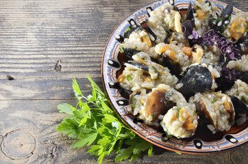 Risotto with mussels  in the plate on a wooden old table/paella/,selective focus