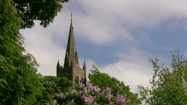 The small market town town of Alston, Cumbria, England with the church spire framed by trees and white summer clouds scudding by.