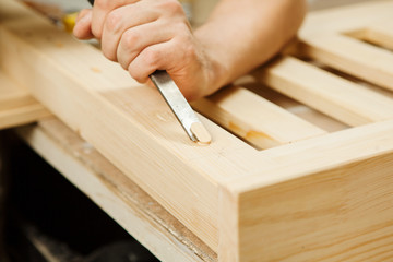 Man working with carving equipment in workshop holding chisel