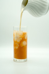 pouring milk into a glass of Thai Milk Tea