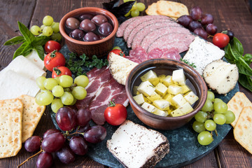 Cheese and meat appetizer selection. Variety of cheese, salami, prosciutto, bread, baguette, grapes, olives