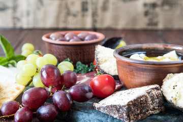 Cheese and meat appetizer selection. Variety of cheese, salami, prosciutto, bread, baguette, grapes, olives