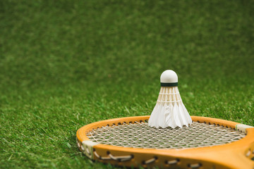 close up view of badminton racket and shuttlecock on green lawn