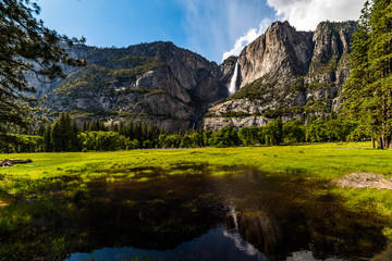 Yosemite Waterfall with blue skies and clouds approaching over the cliffs