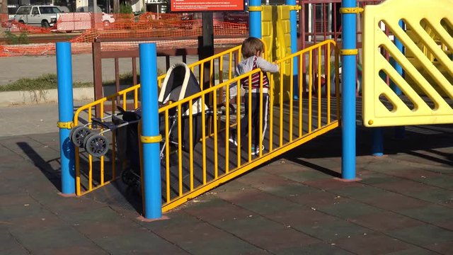 4K Kid works really hard to get his pushchair on hill, falling and rising, finally wins
