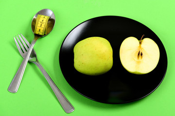 Apple halves set lying on black ceramic plate near cutlery