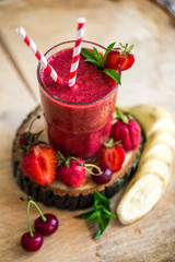 Composition of glass with fresh berry smoothie served with berries on wooden table.