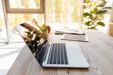 laptop and digital tablet on wooden tabletop at modern office