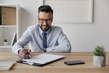 portrait of cheerful businessman with pen in hand looking at blank paper