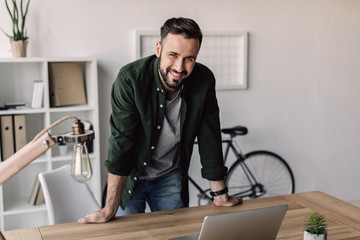 smiling bearded businessman leaning on table in modern office