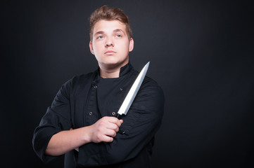 Proud young chef posing with sharp knife